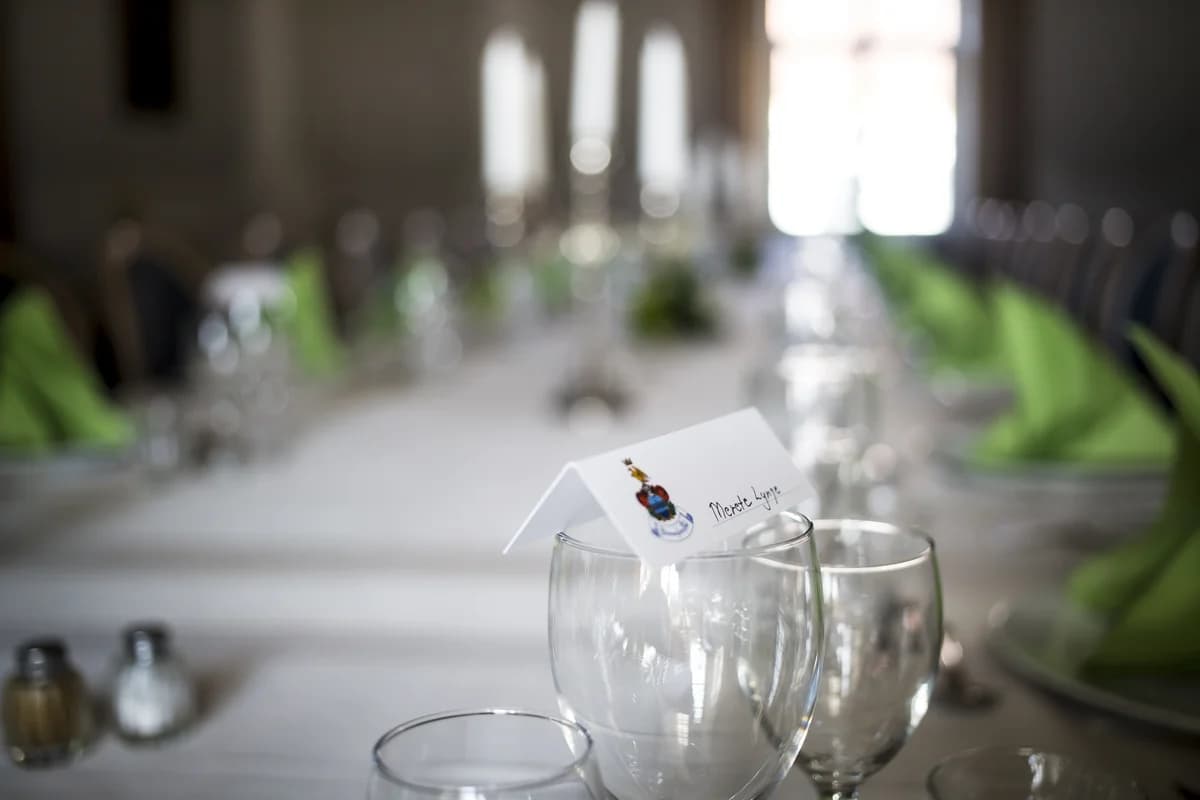 A name card in a wine glass on a decorated banquet table.