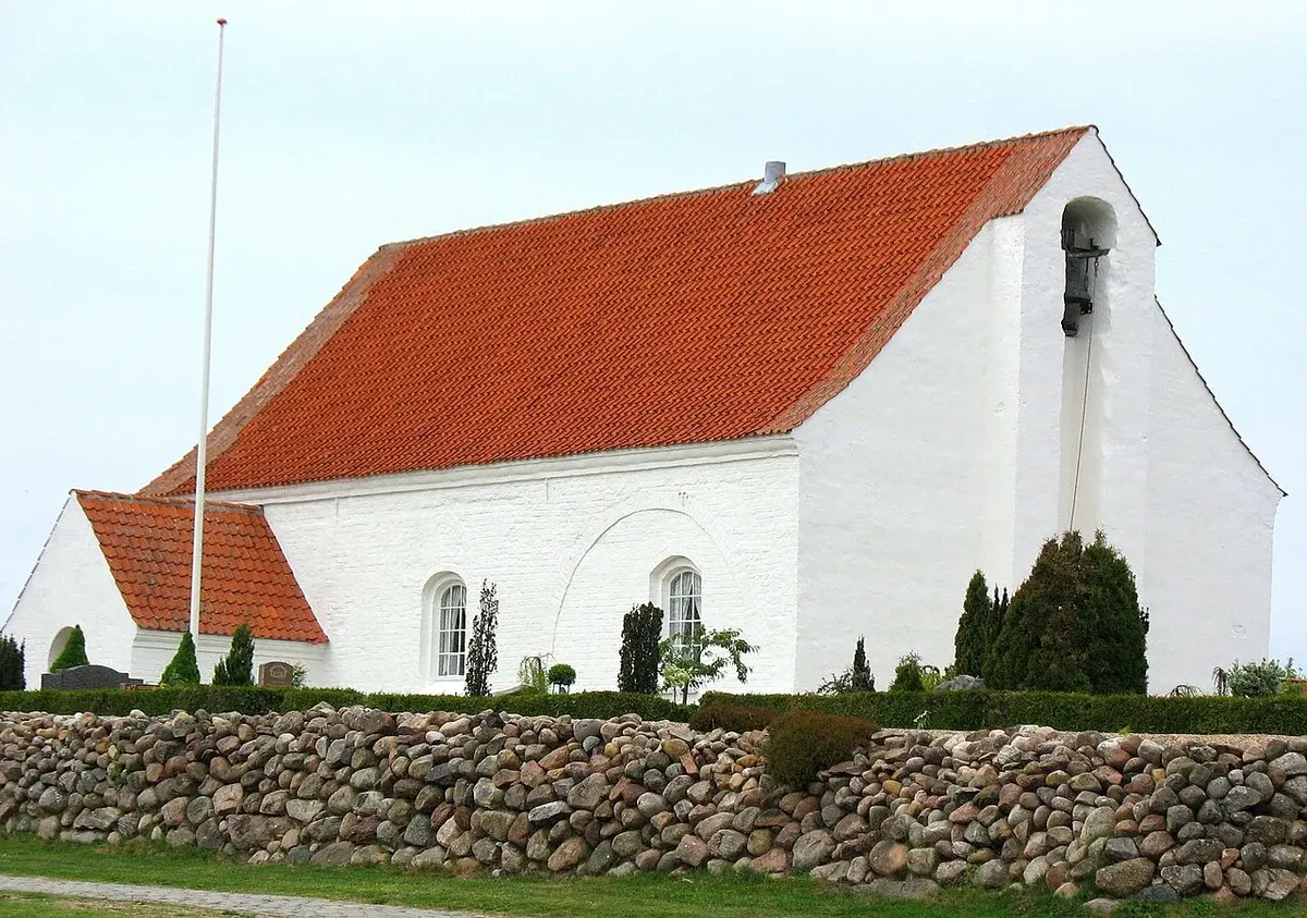 Exterior of a simple white church with a red roof in Denmark.