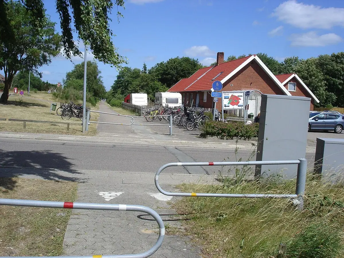 A bike and pedestrian path crossing a road near a brick building in Kølvrå.