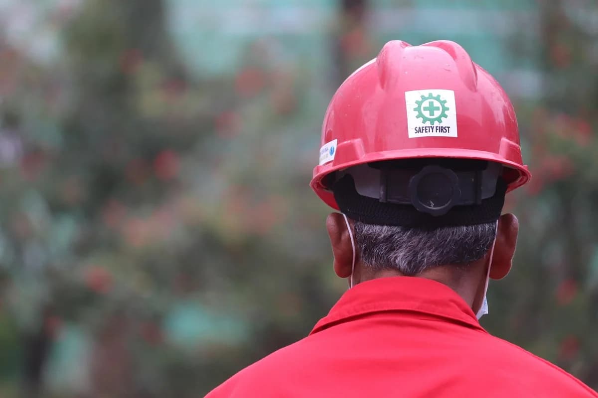 Back view of a construction worker wearing a red safety helmet.