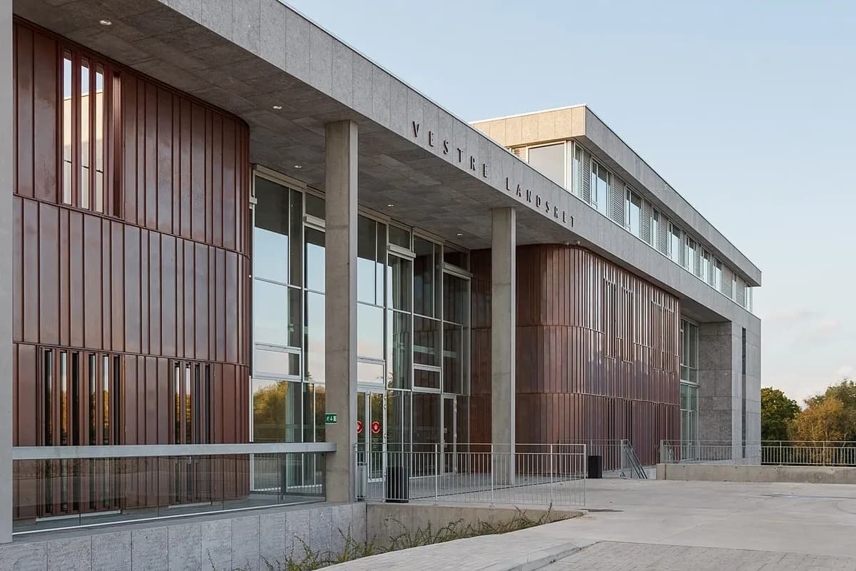 Modern courthouse entrance with glass and copper-colored facade in daylight.