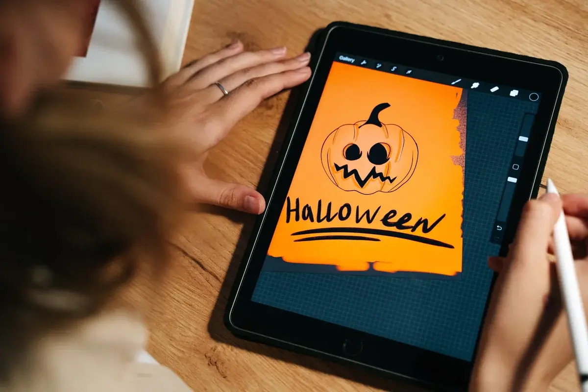 A tablet displaying a Halloween pumpkin drawing with a stylus nearby.