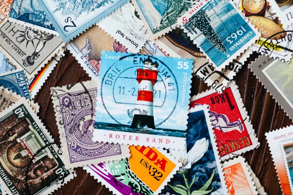 Assorted colorful vintage postage stamps spread out on a wooden surface.